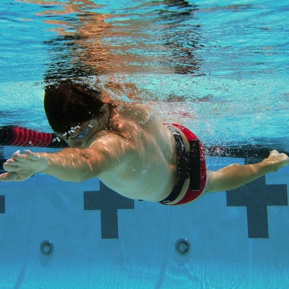 Audible hip rotation swimming training aid