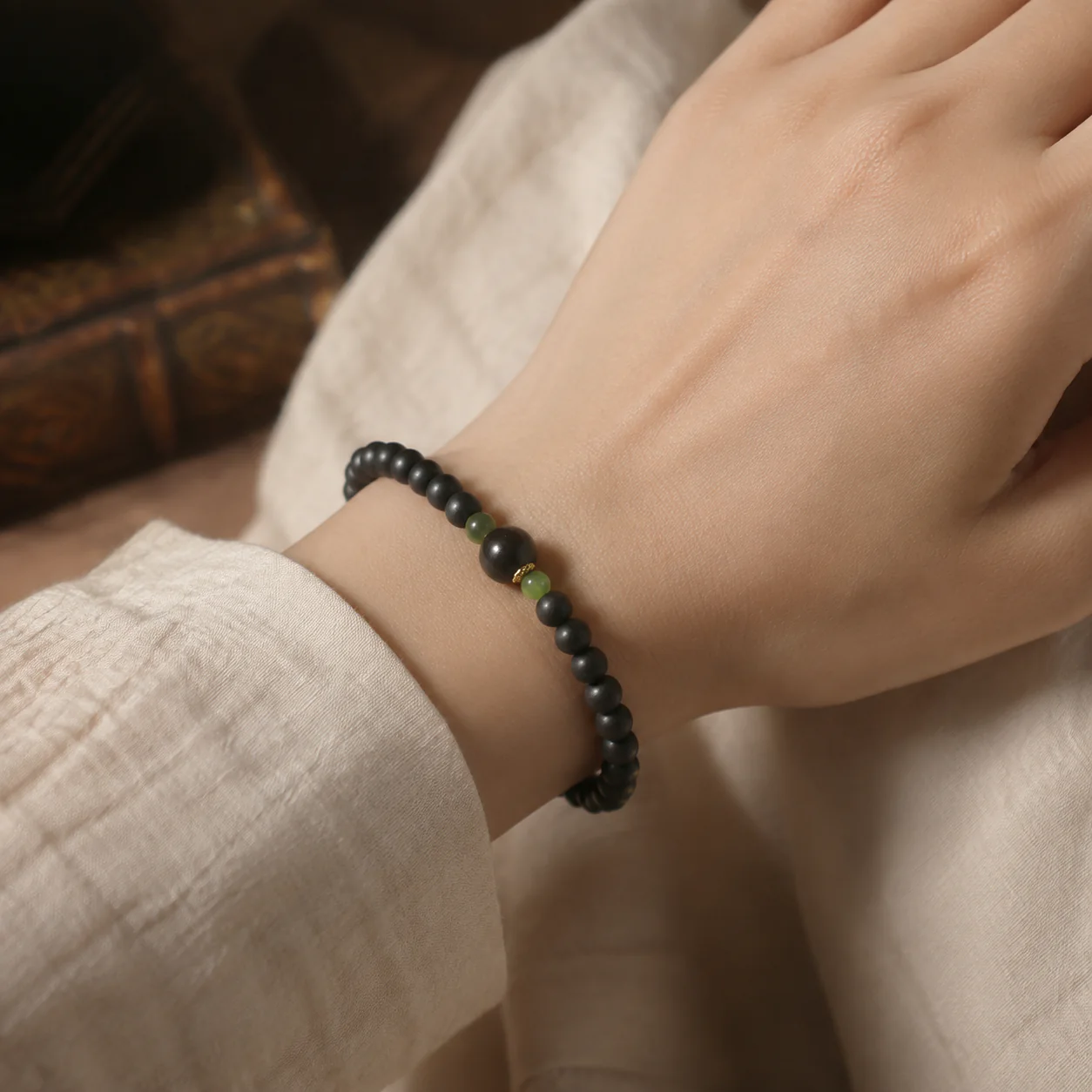 Dark incense bead bracelet with green accent worn with linen