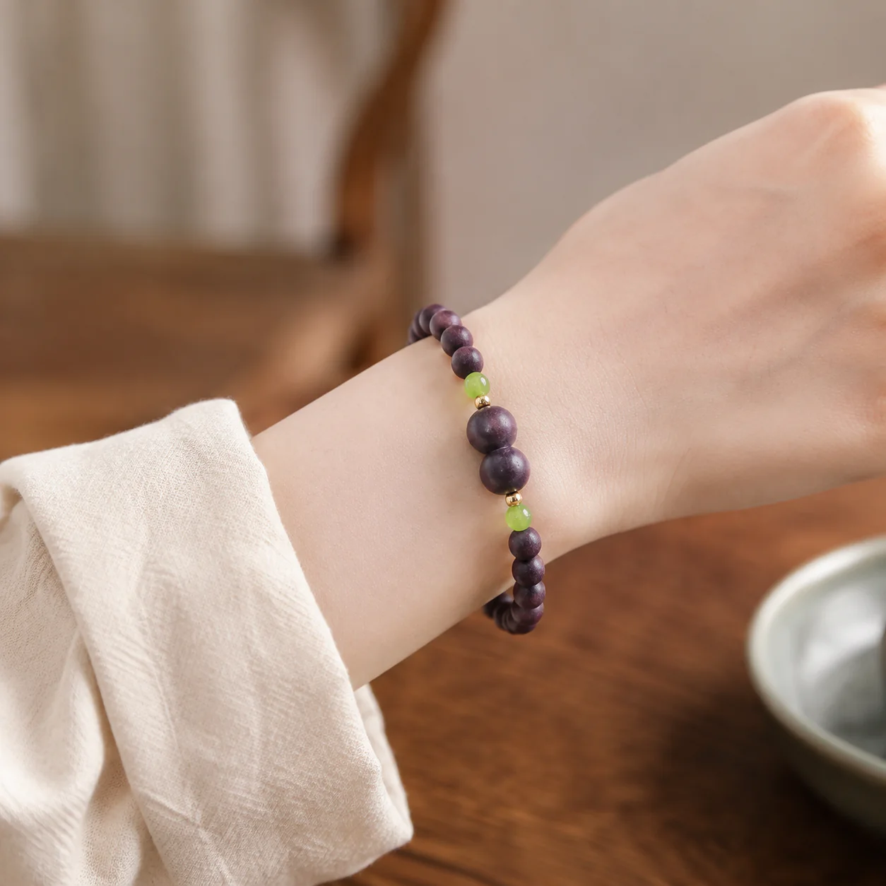 Plum wood bead bracelet with green stone accents worn with linen