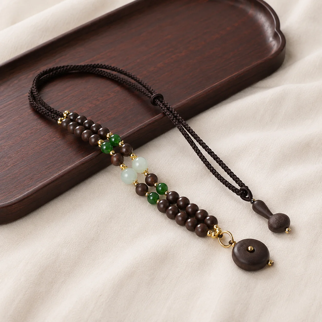 Dark wood bead necklace with green accents in a refined setting