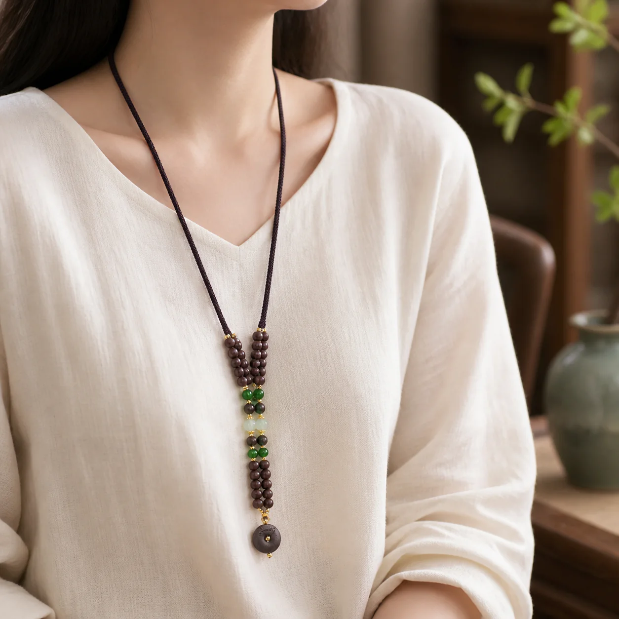 Dark wood bead necklace with green accents worn with linen