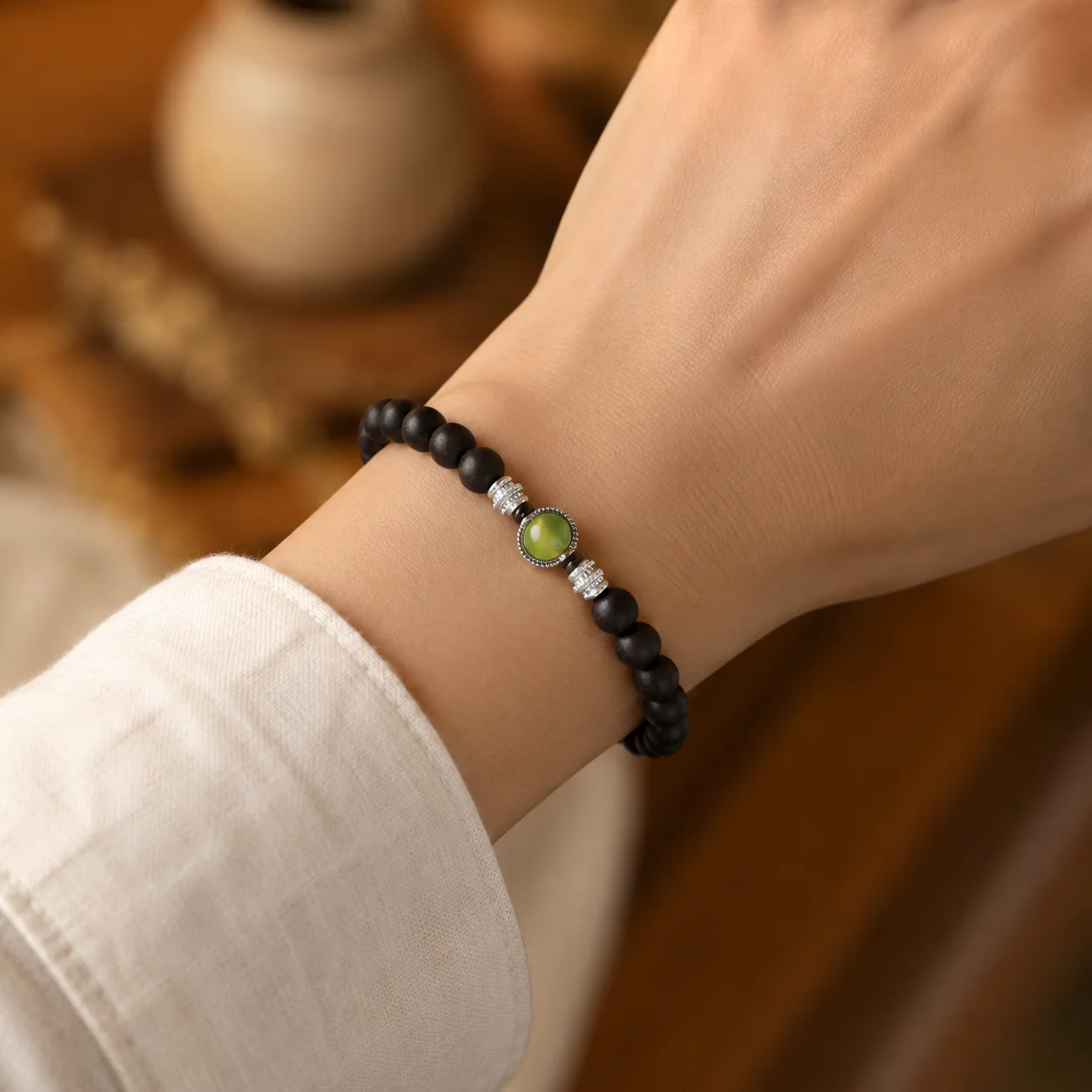 Dark wood bead bracelet with green gemstone worn with linen