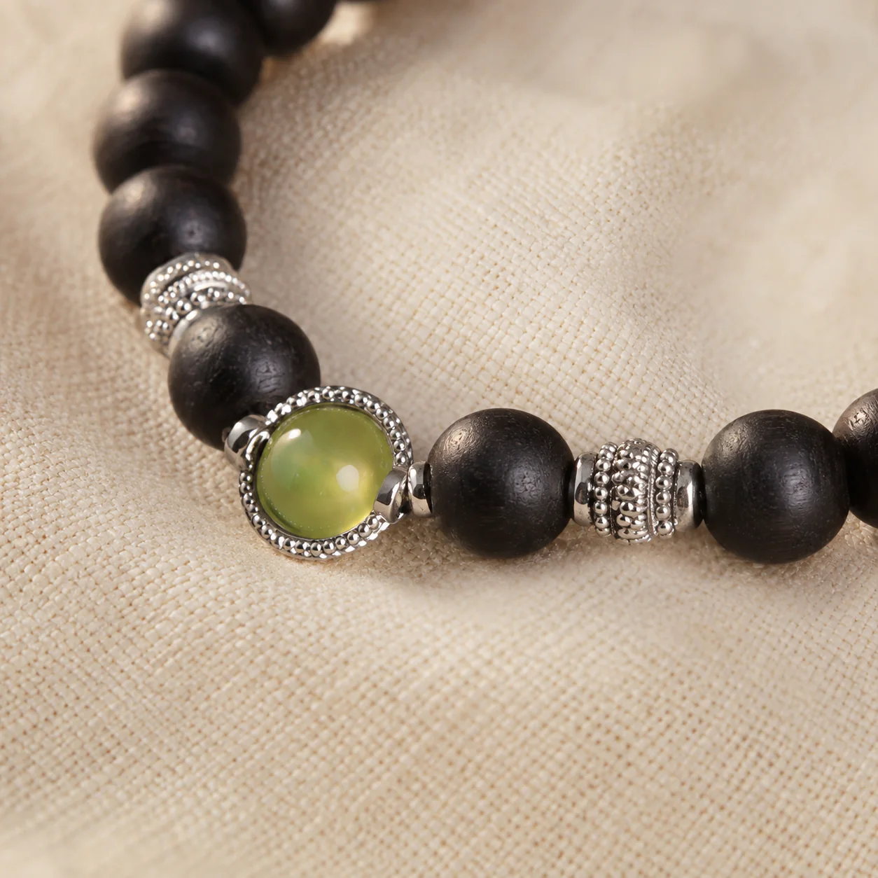Dark wood bead bracelet with green gemstone material detail