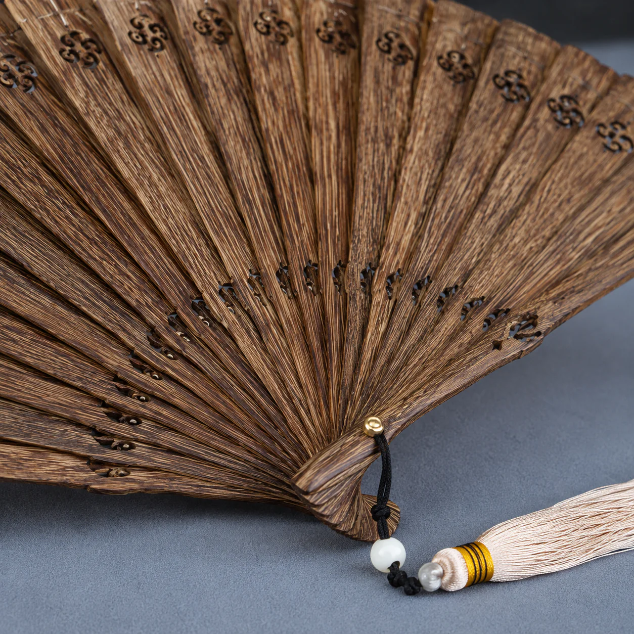 Agarwood folding fan pivot and tassel detail