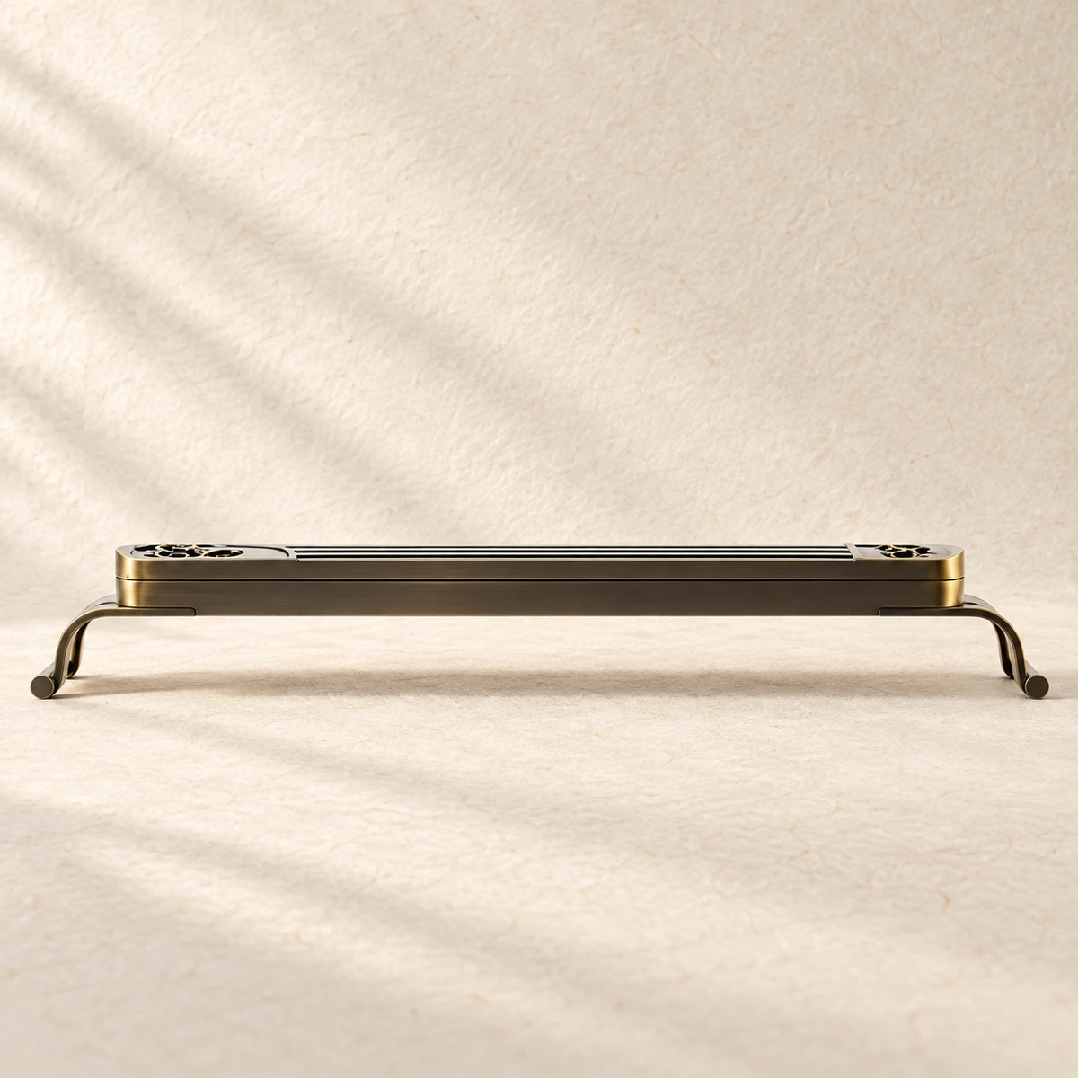 Low-profile metal incense holder on warm ivory paper