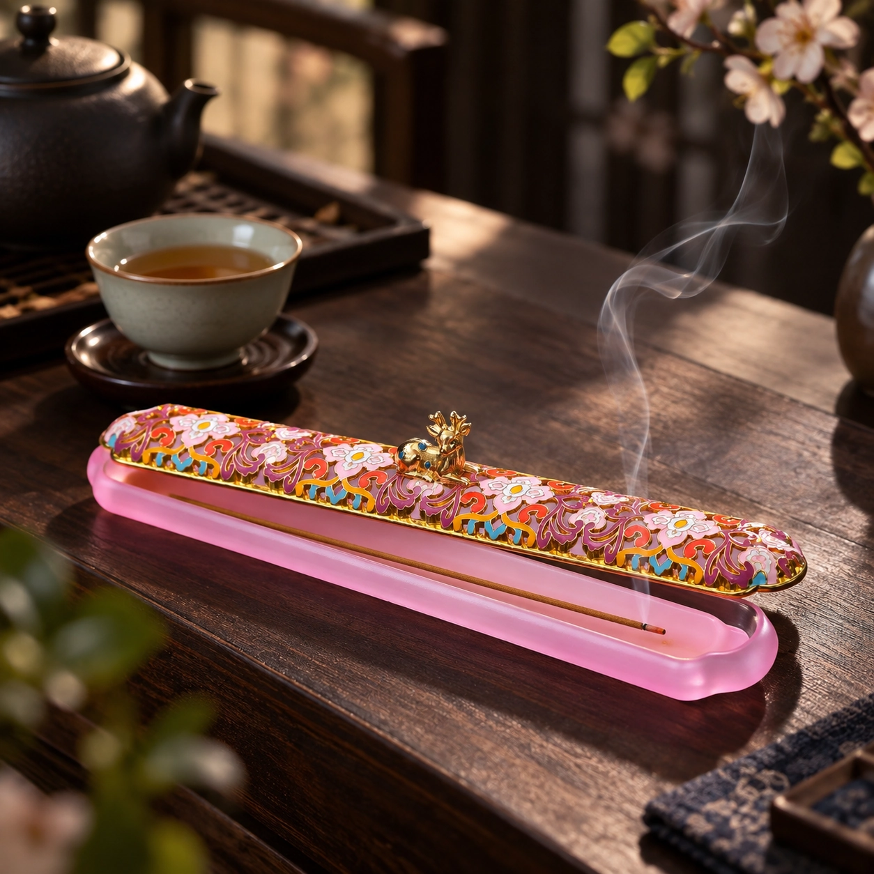 Soft pink deer motif incense box on a tea table with incense smoke