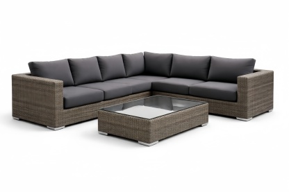 Divano angolare modulare in rattan sintetico con cuscini grigi e tavolino in vetro temperato