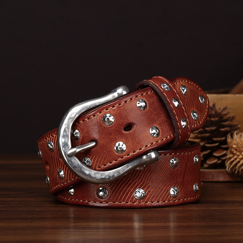 Close-up of hand-set silver alloy studs on full-grain leather with antique silver buckle