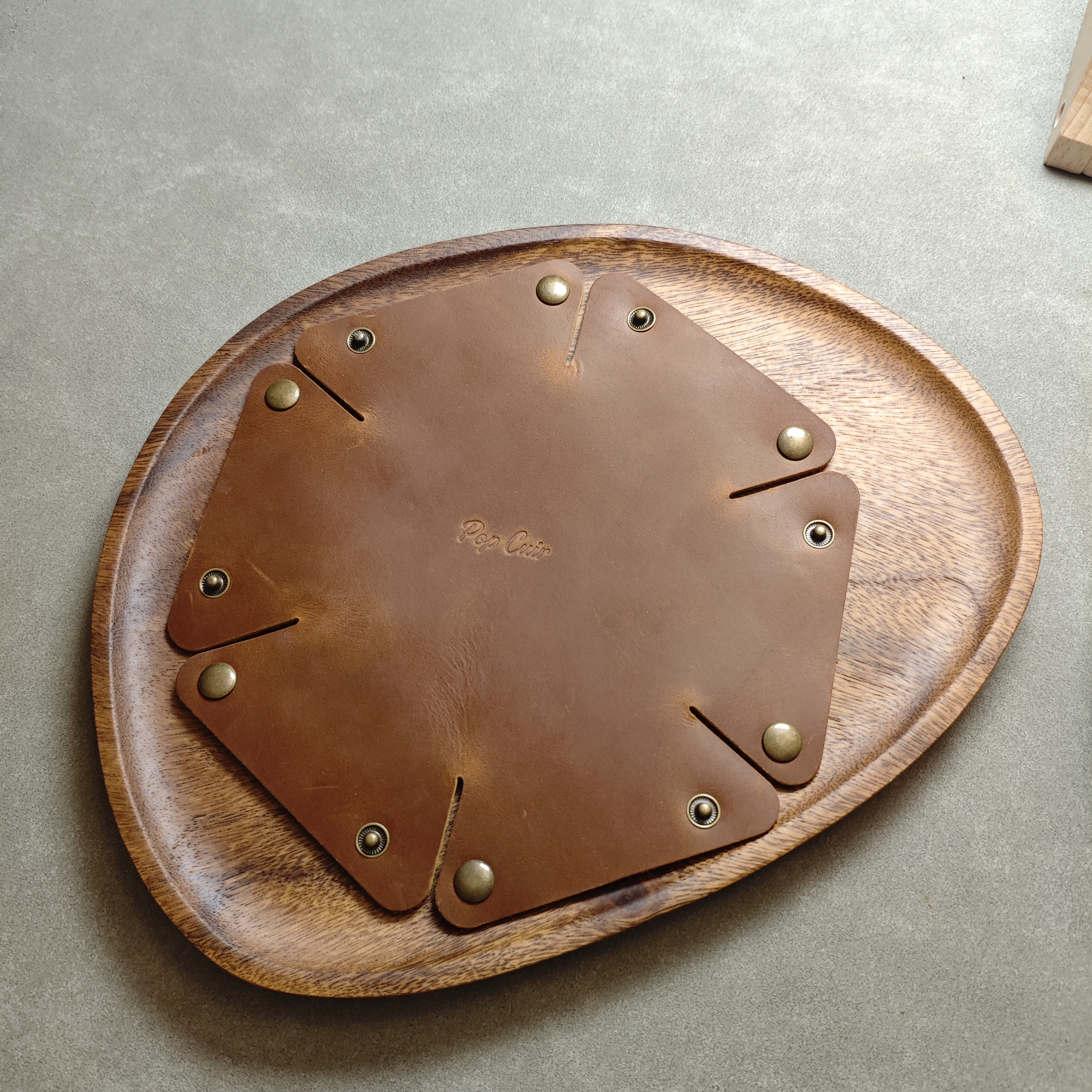Flat state full view of crazy horse leather valet tray with brass snaps arrayed around center