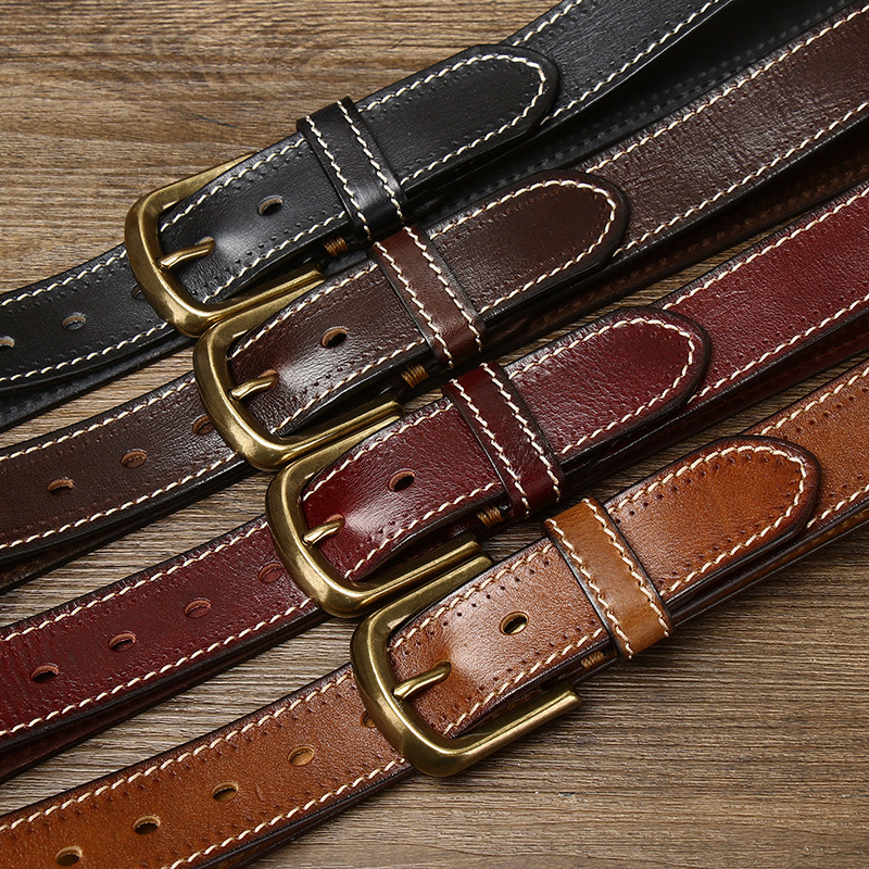 Four color variants of vintage full-grain leather belt with brass pin buckle laid out on rustic wood &mdash; Black, Burgundy, Dark Brown, Tan