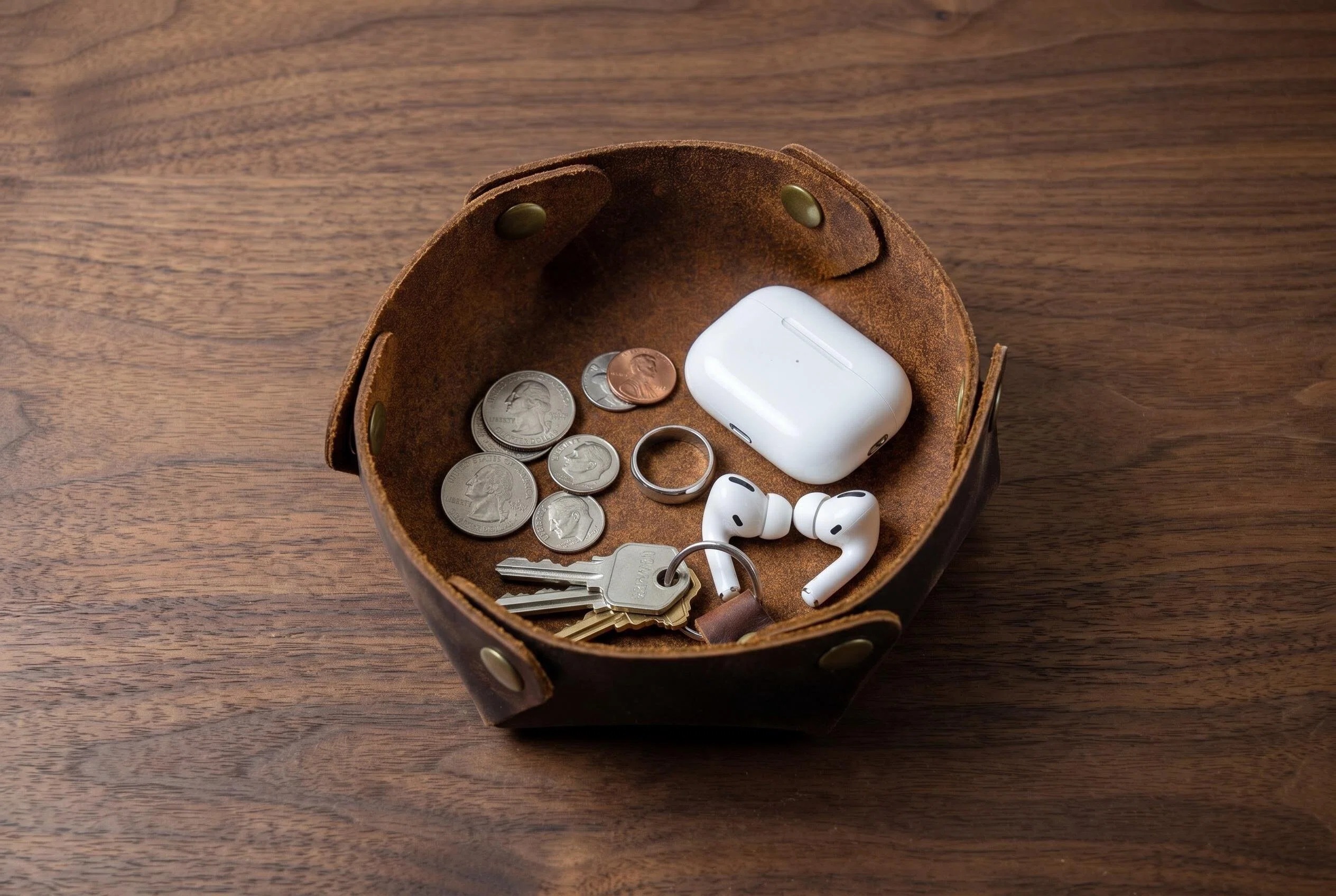 Assembled crazy horse leather valet tray filled with coins keys ring and everyday carry items