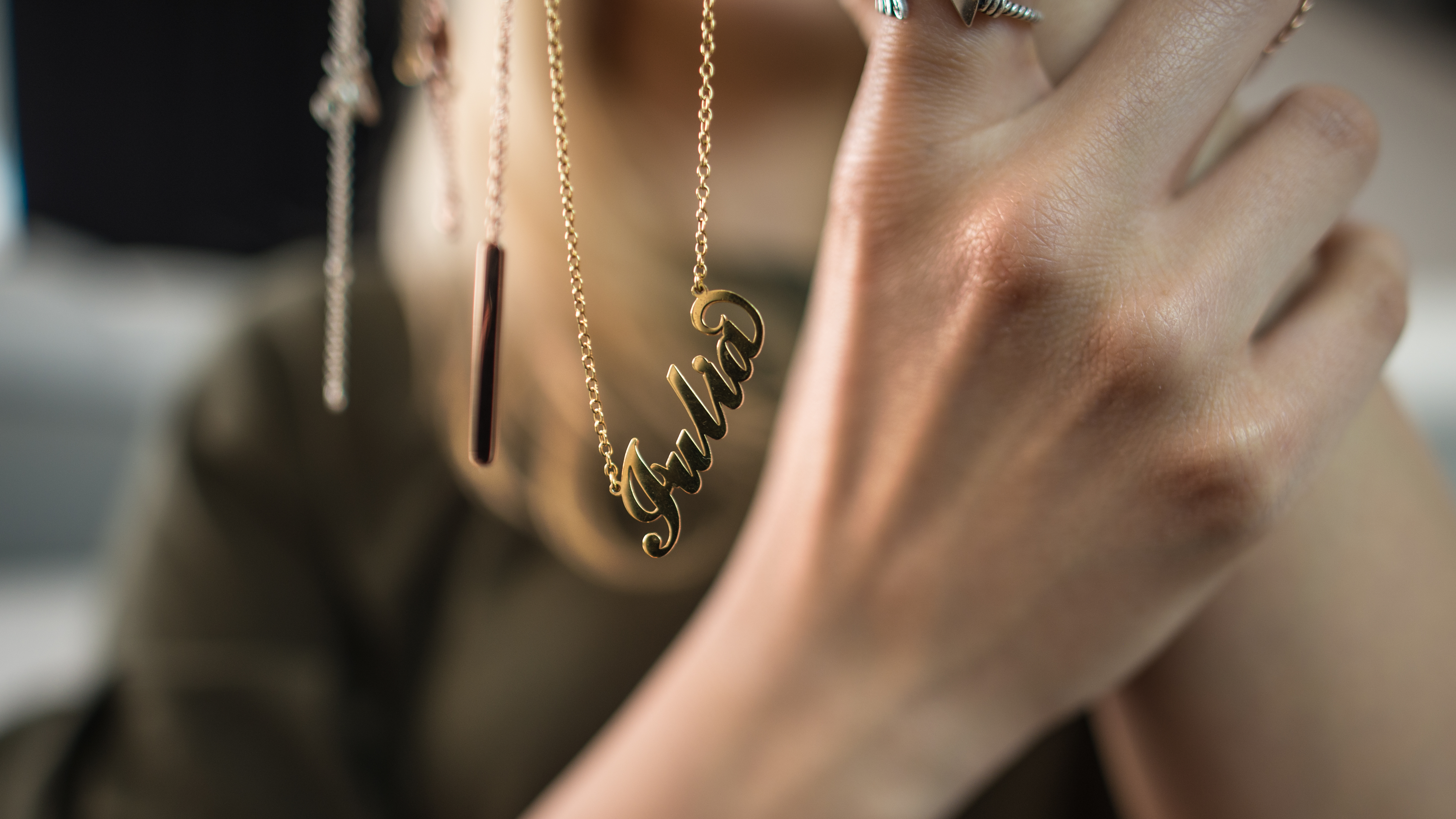 A women holding a personalized necklace with her name on it