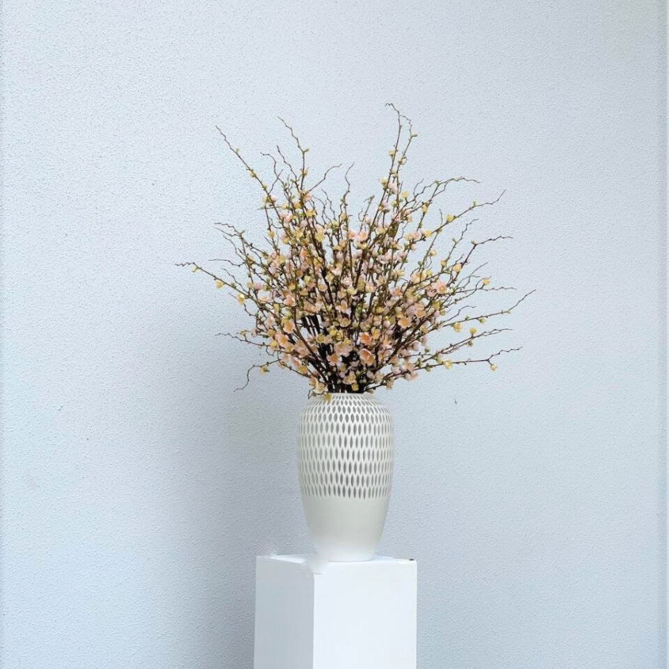 Fleurs de cerisier roses dans un vase pélican