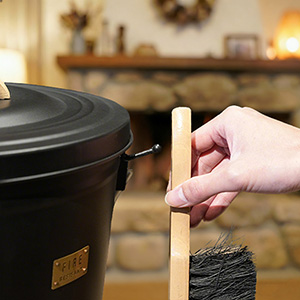Hand lifting the wood-handled broom from its bucket-side hook