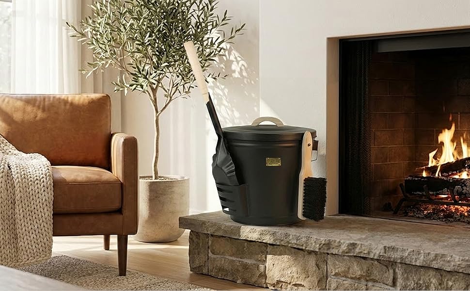 Black ash bucket and tools on a stone hearth beside a fireplace