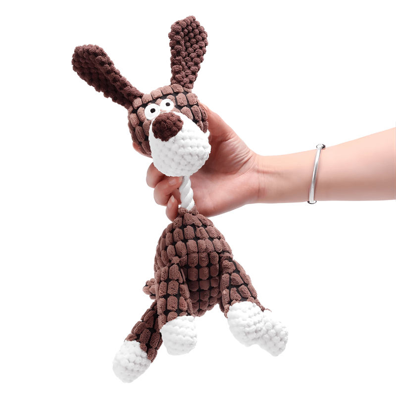 Hand holding a brown knitted dog toy with a white rope