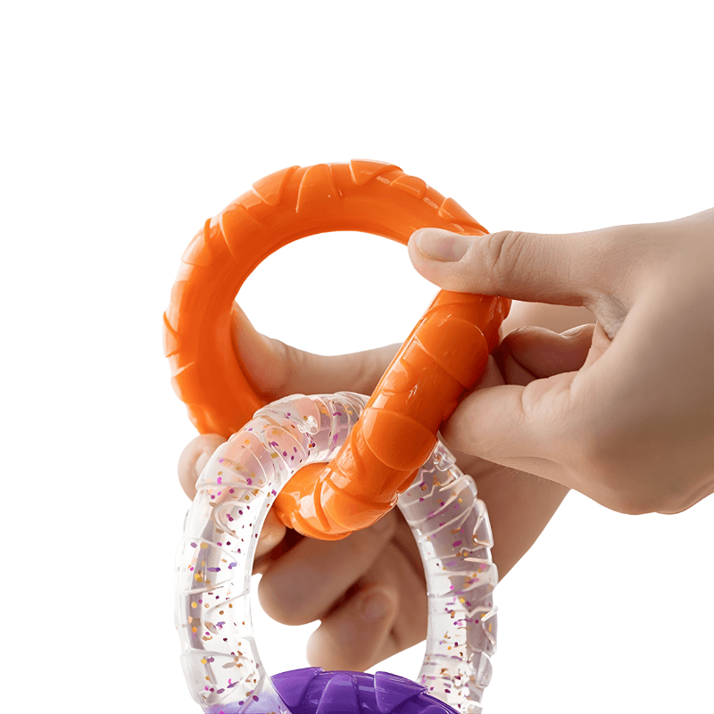 Hand holding an orange textured ring with a clear and purple ring underneath on a white background