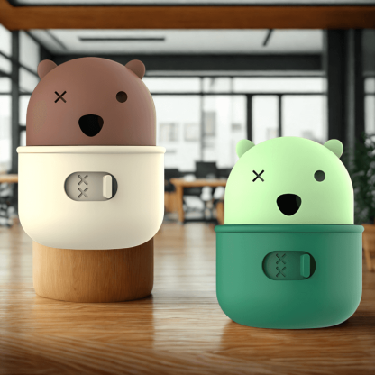 Two cute animal-shaped speakers, one brown and one green, on a wooden surface.