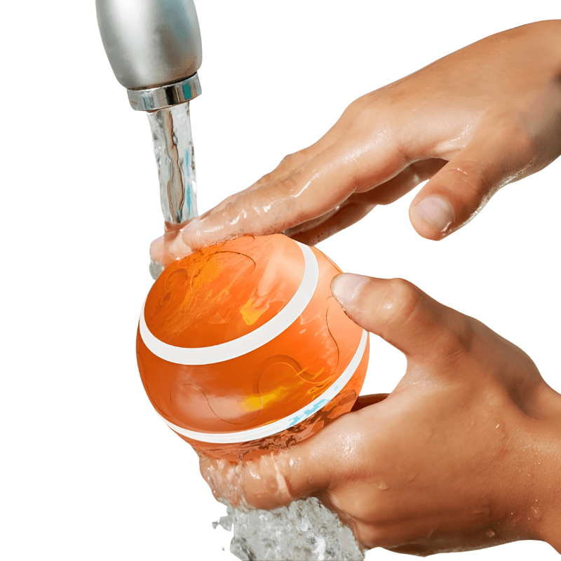 Person washing an orange ball under running water from a faucet.