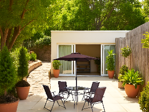 A lush garden terrace with green hedges, stone flooring, and soft natural lighting