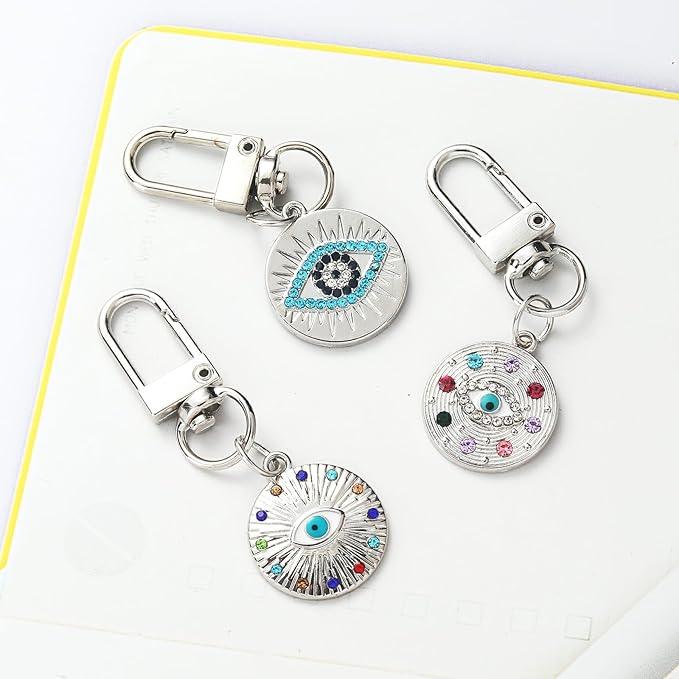 three Silver Gold Evil Eye Keychain for Women Protection Good Luck Charms Key Chain for Car Keys Holder Bag Purse featuring a clean chic eye design and silver and multi color ,perfect for daily /party/casual/office bagcharm/chain charm decoration . Styled against a white  background.