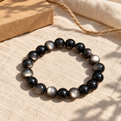 Silver sheen obsidian bracelet on linen beside a wooden box