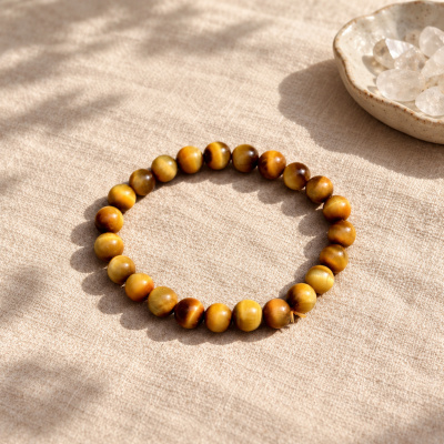 Golden tiger eye bracelet on linen beside a dish of clear quartz chips