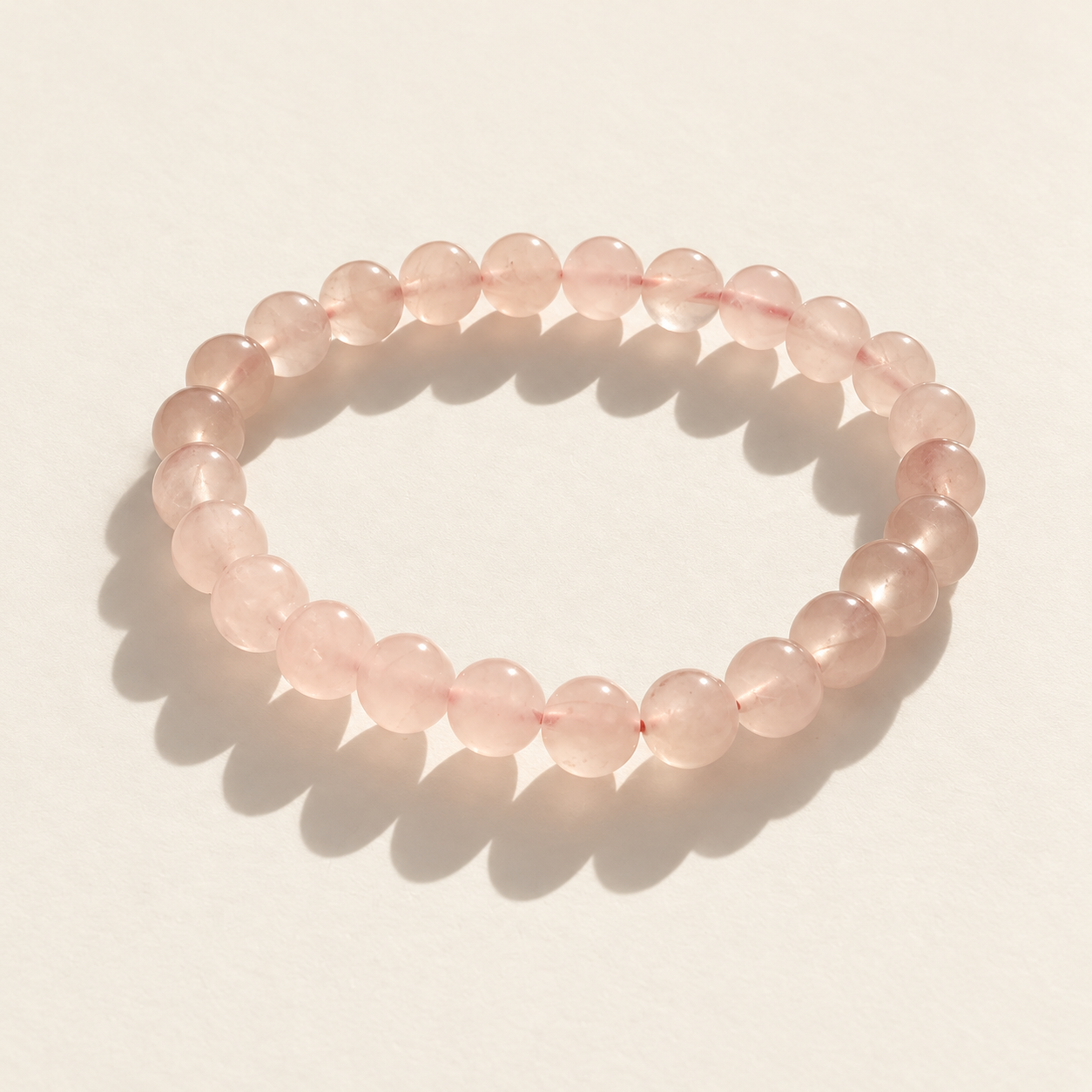 Pale grapefruit-pink crystal bracelet on a softly lit ivory surface