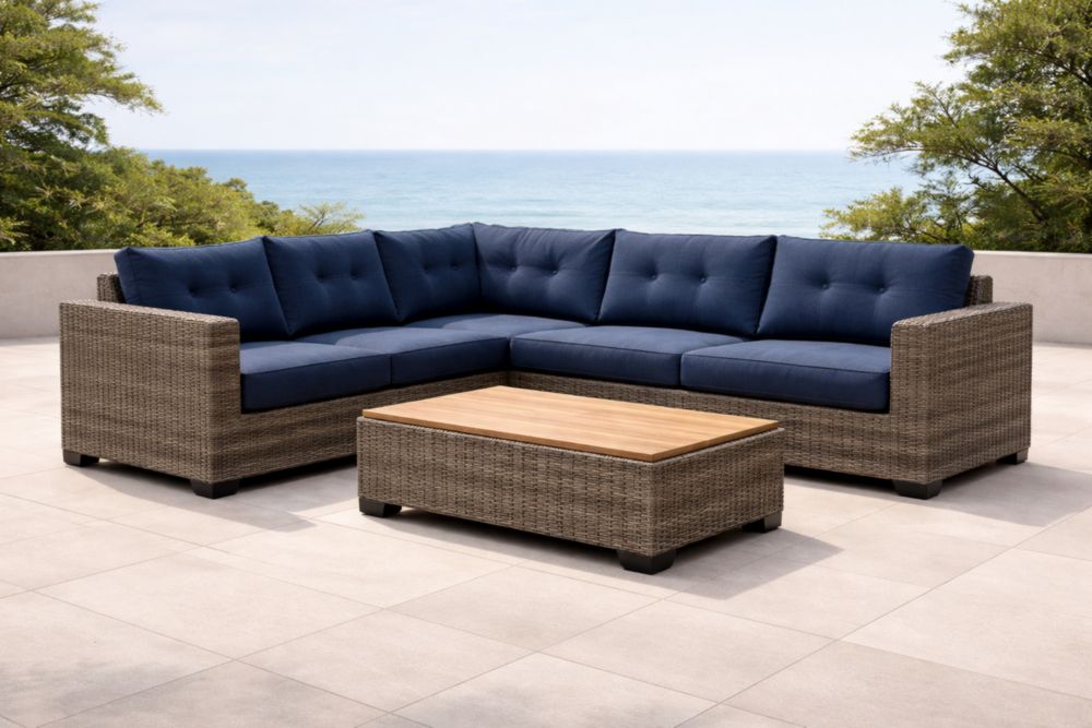 Divano angolare in rattan con cuscini blu e tavolino in teak