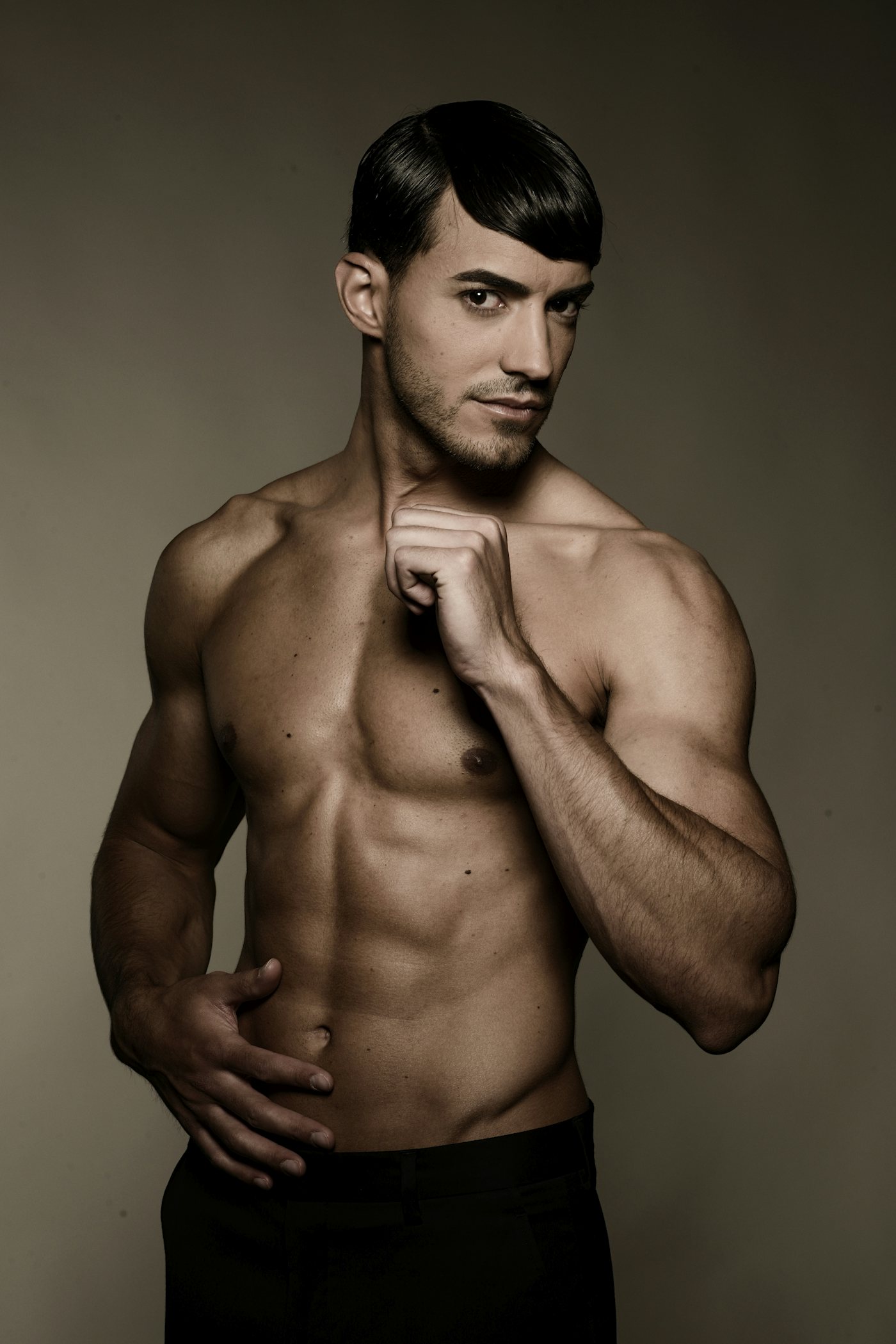 A fit male model in swim trunks in a studio portrait