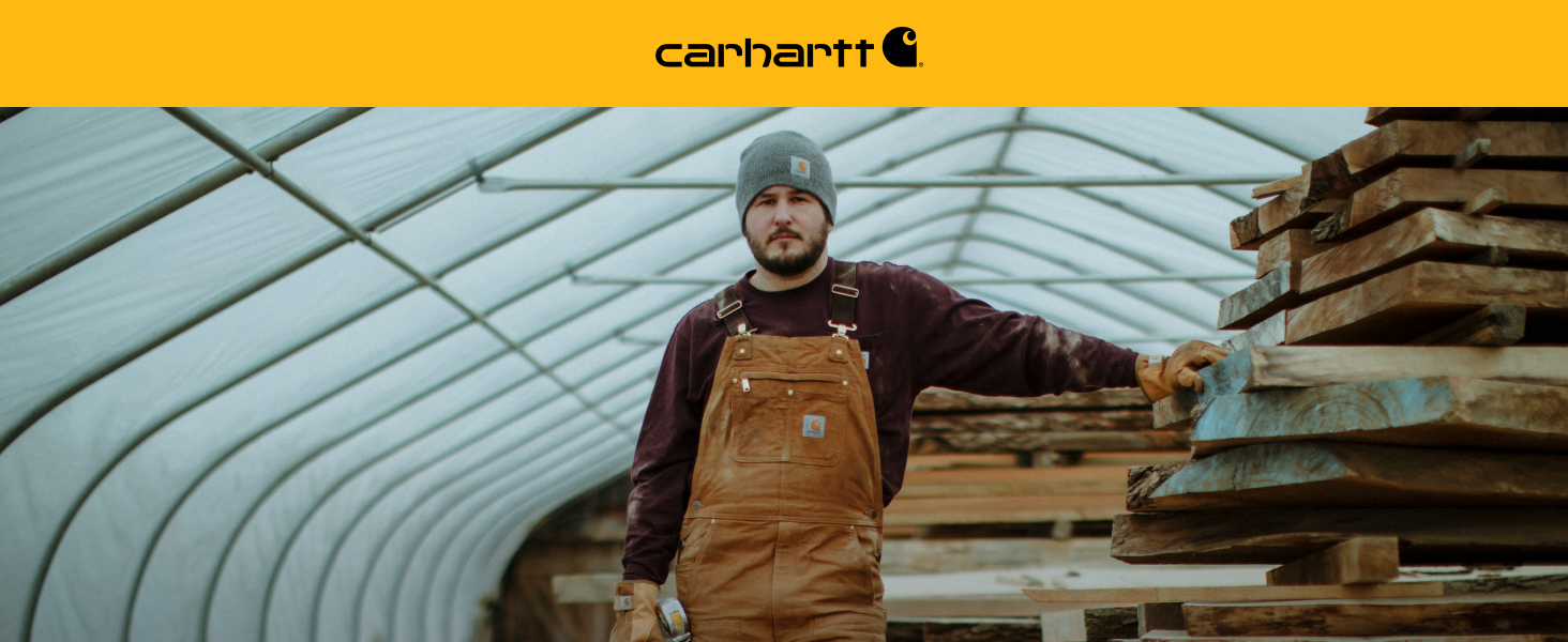 Man wearing Carhartt Men's Unlined Duck Bib Overalls showing durable fabric made for rugged work.