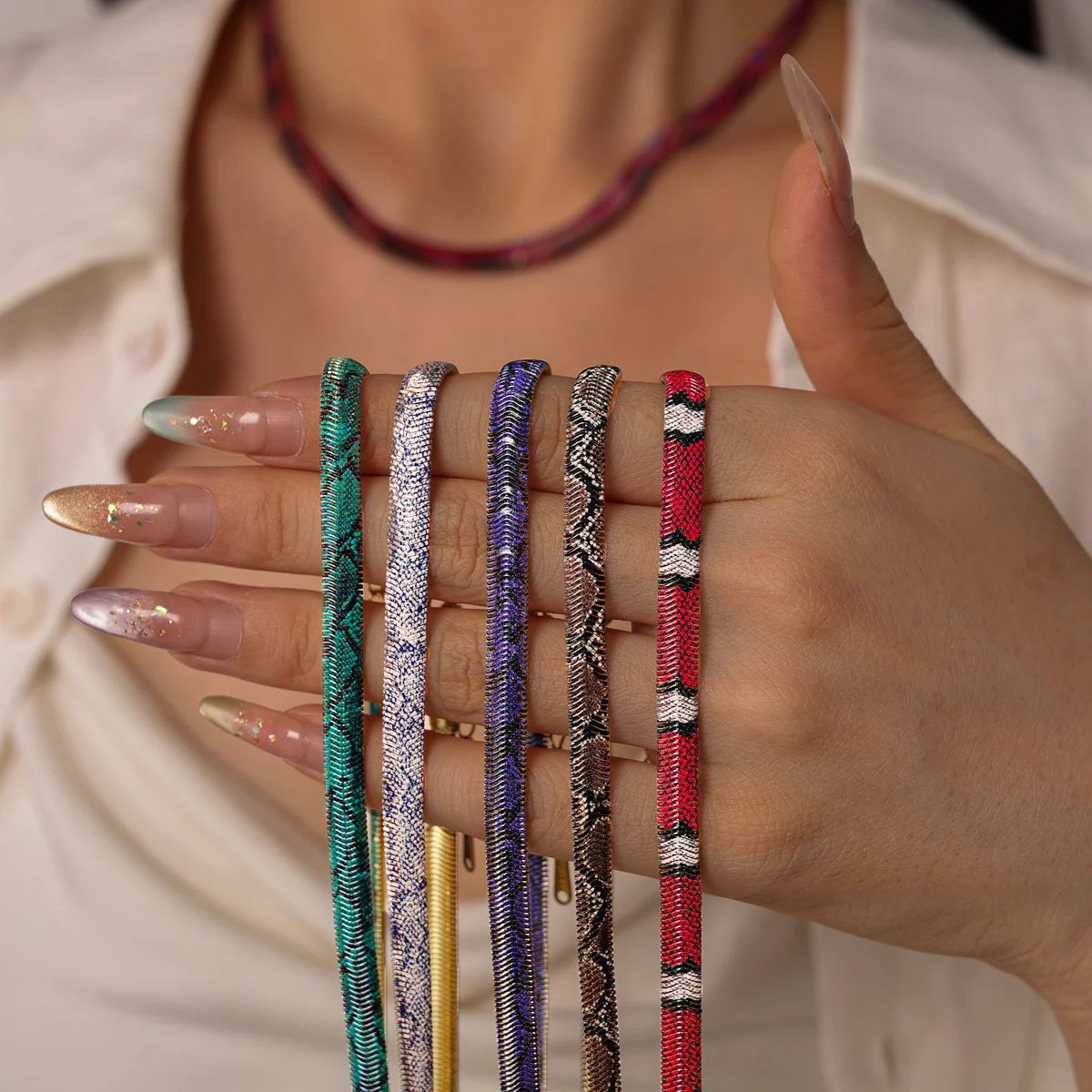Close-up of multiple serpent-inspired necklace colors and metallic surface patterns