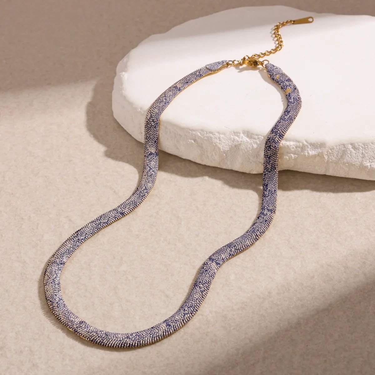Pale porcelain and blue patterned snake-texture necklace on stone