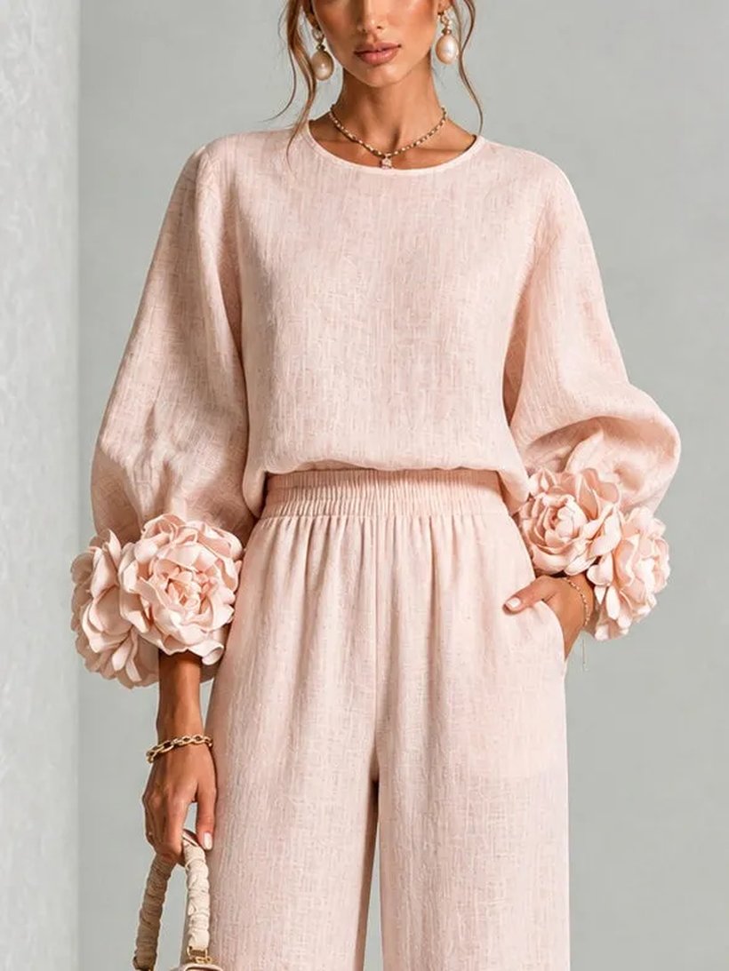 Detail of the linen top: round neck, lantern sleeves and the 3D camellia cuffs