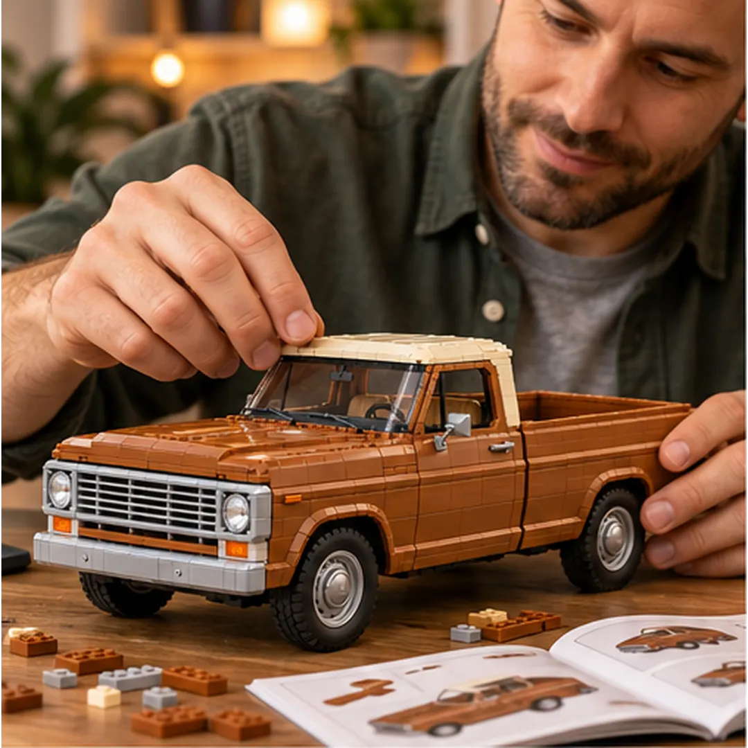 Adult builder working by hand on the cream roof of a brown vintage pickup brick model with loose building pieces and an illustrated guide on the table