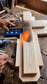 Torch-burning the wooden cross by hand