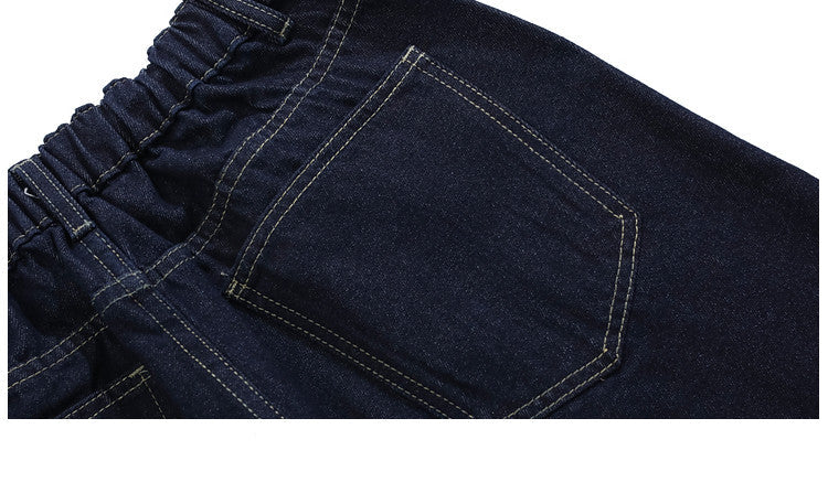 Close-up of dark blue jeans with a pocket detail on a white background.