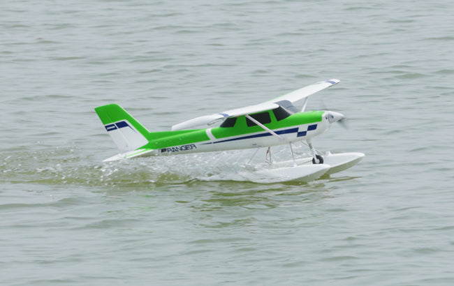 Un pequeño hidroavión verde y blanco deslizándose sobre un lago tranquilo.