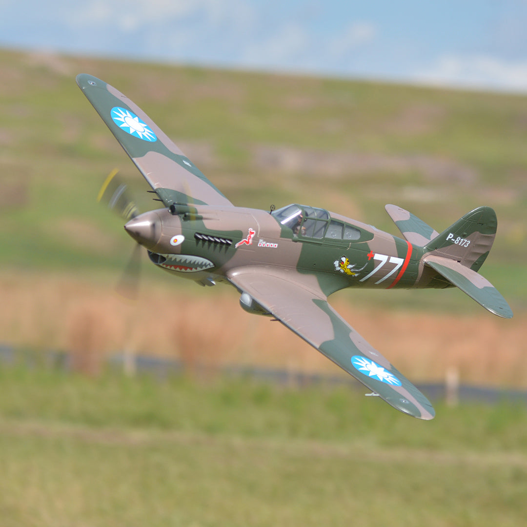 FMS 1400mm P-40B Warhawk Flying Tiger PNP RC airplane in flight, featuring camouflage paint and shark mouth decal.