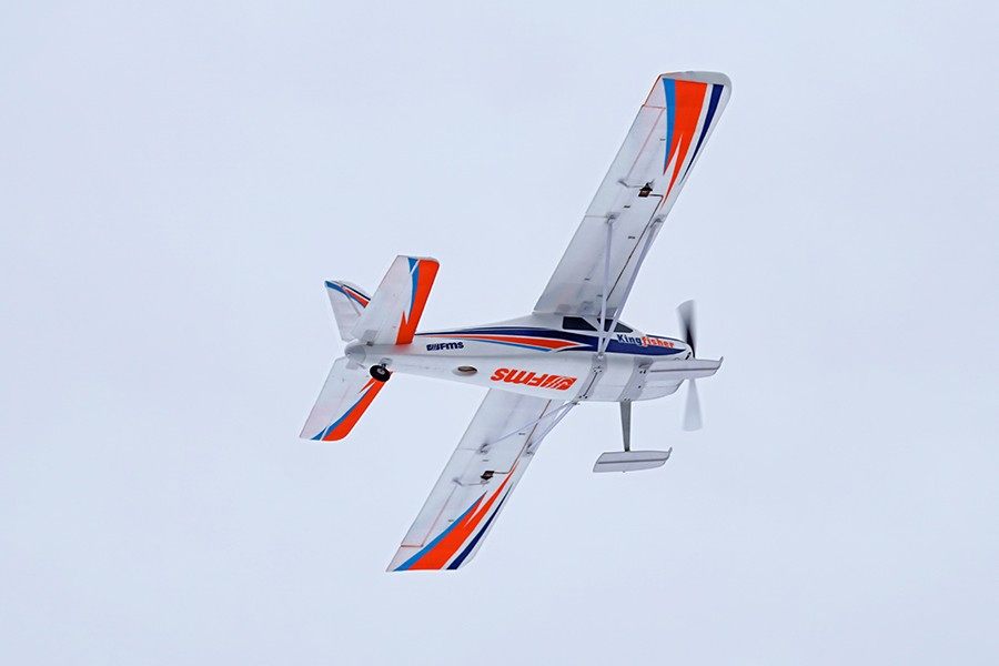 FMS 1400mm Kingfisher PNP remote control airplane in flight, white with orange and blue accents.