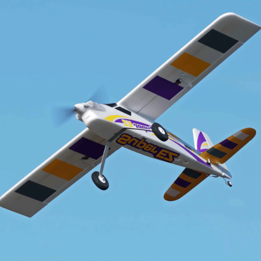 FMS 1220mm Super EZ V4 RC airplane in flight, white with purple and orange accents.