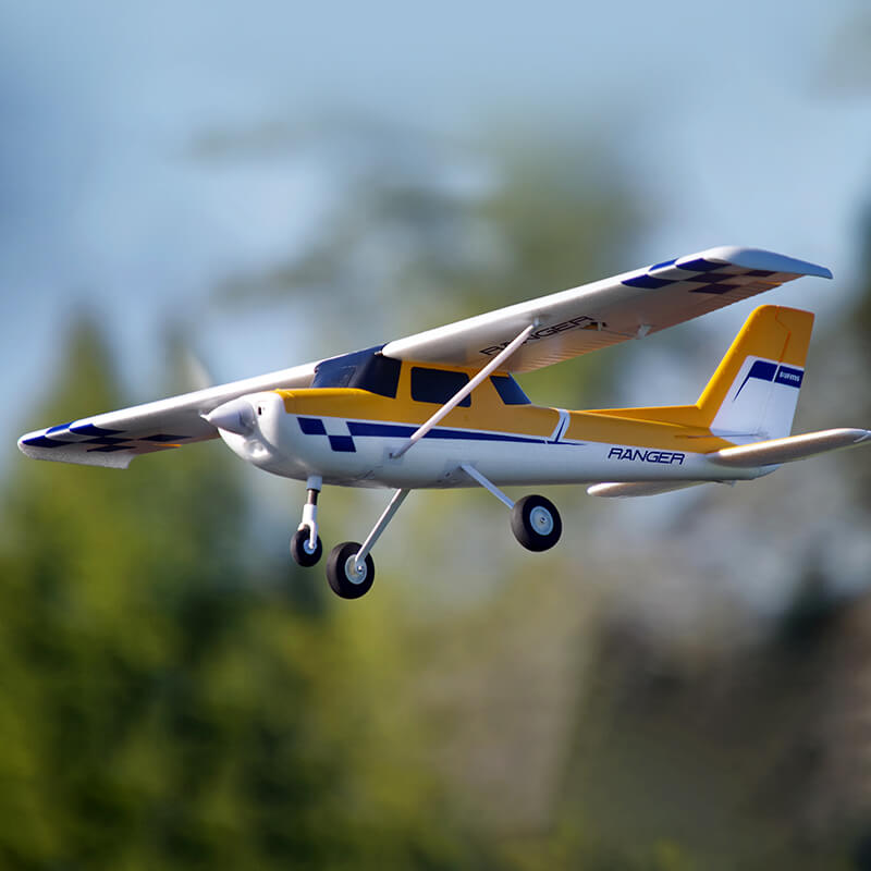 FMS Ranger V2 RC airplane soaring through the sky in bright yellow and white colors