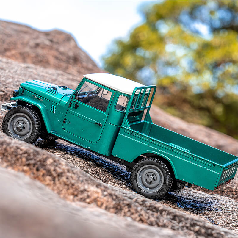 FMS 1:12 teal green Toyota FJ45 pickup truck with white roof on rocky terrain