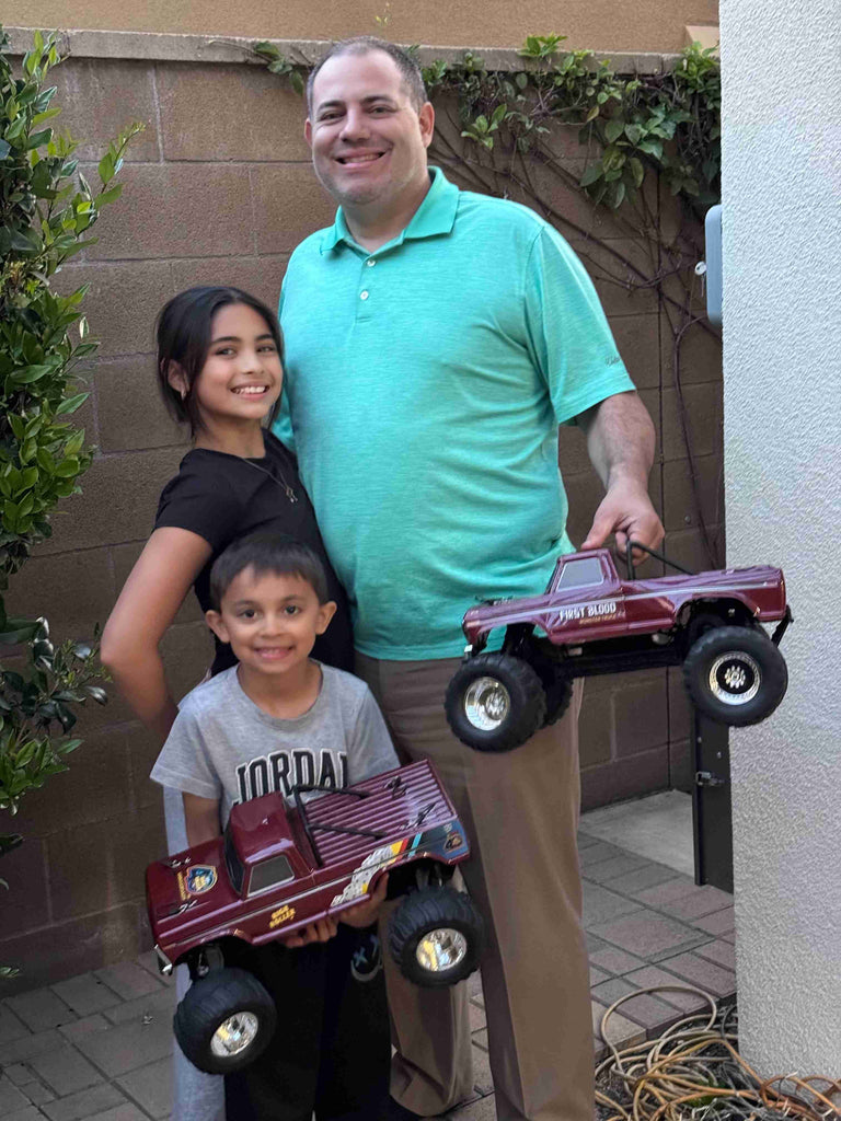 Familia posando con sus camiones monstruo teledirigidos.