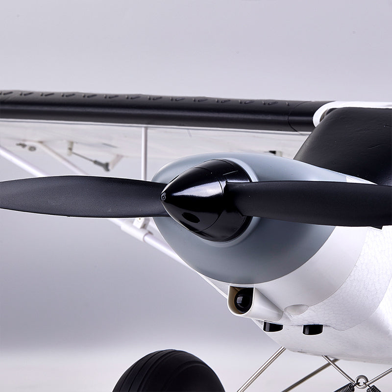 FMS 1300mm PA-18 Super Cub RC plane front view: black propeller, grey/white cowling, camera.