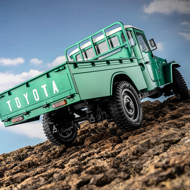 Green FMS 1:12 TOYOTA FJ45 pickup truck model on rocky terrain