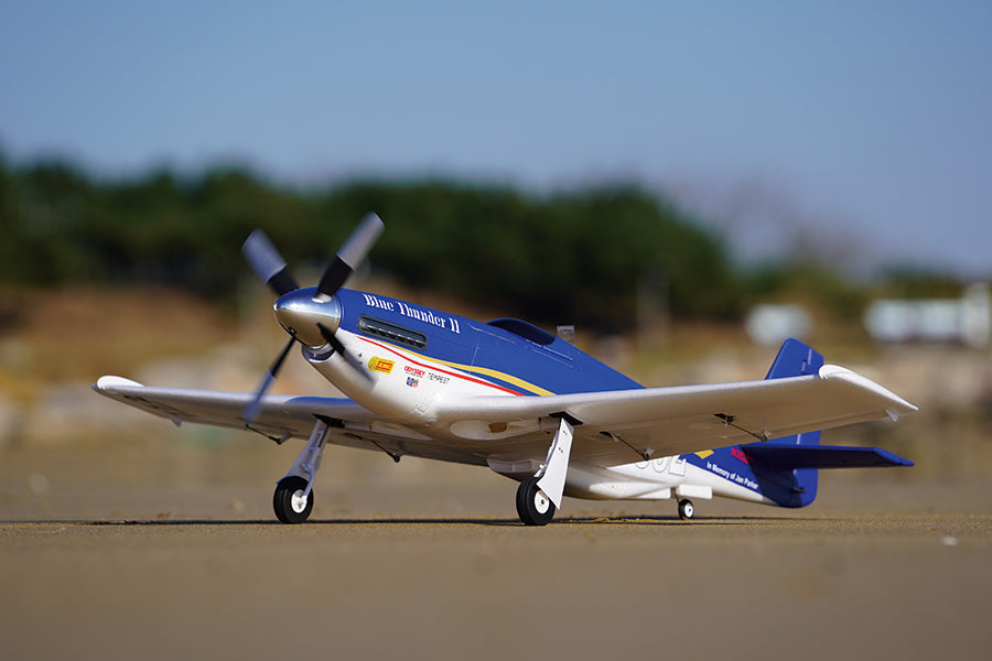 FMS 1100mm P-51 Mustang V2 PNP RC airplane, blue with yellow and red accents, on ground.