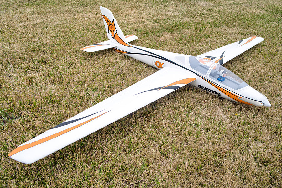 FMS 3000mm Fox Glider PNP on grass with orange trim. Features fox logo and FMS branding. Aerodynamic design.