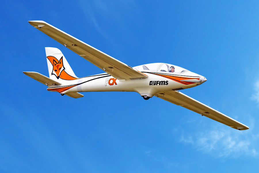 FMS 3000mm Fox aerobatic glider in flight, white with orange fox graphics.