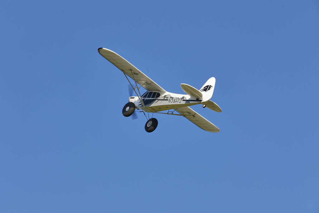RC aircraft flying against clear blue sky backdrop